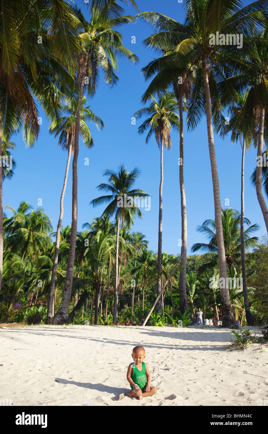 Kleiner Junge am Strand unter Palmen sitzen; Las Reetdächern; El Nido; Palawan; Philippinen Stockfoto
