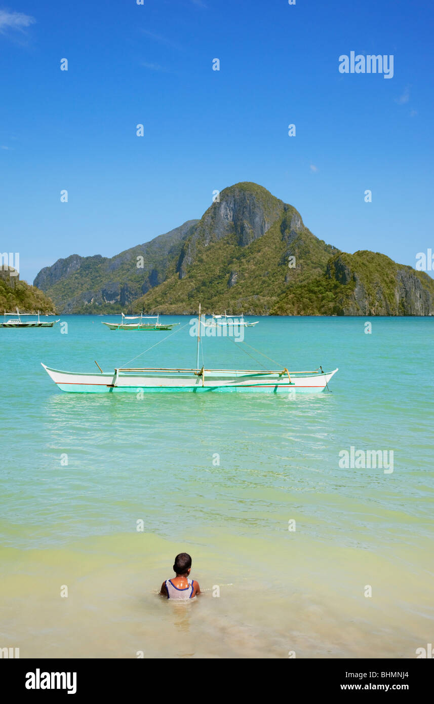 Junge sitzt im Meer Banca Boot und Cadlao Insel zu betrachten; El Nido; Bacuit Bay; Palawan; Philippinen. Stockfoto