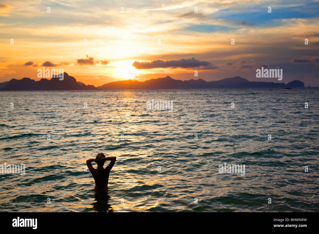 Silhouette eines Mädchens im Meer einstellen ihr Haar bei Sonnenuntergang; Las Cababnos; El Nido; Bacuit Archipels; Palawan; Philippinen Stockfoto