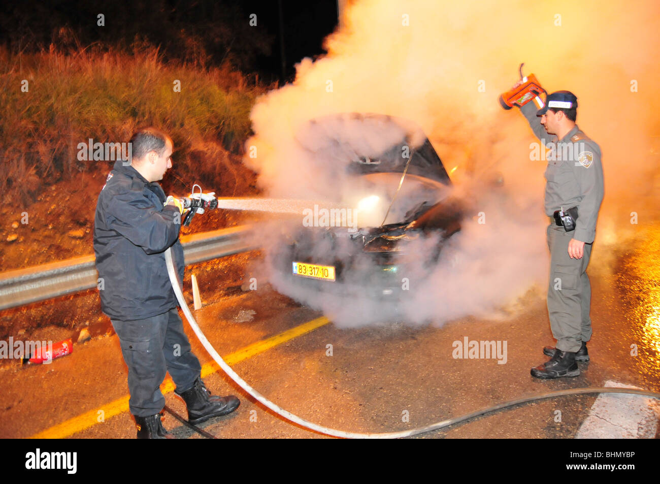 Israel, Northern District, Feuerwehrleute löschen ein brennendes Fahrzeugs Stockfoto