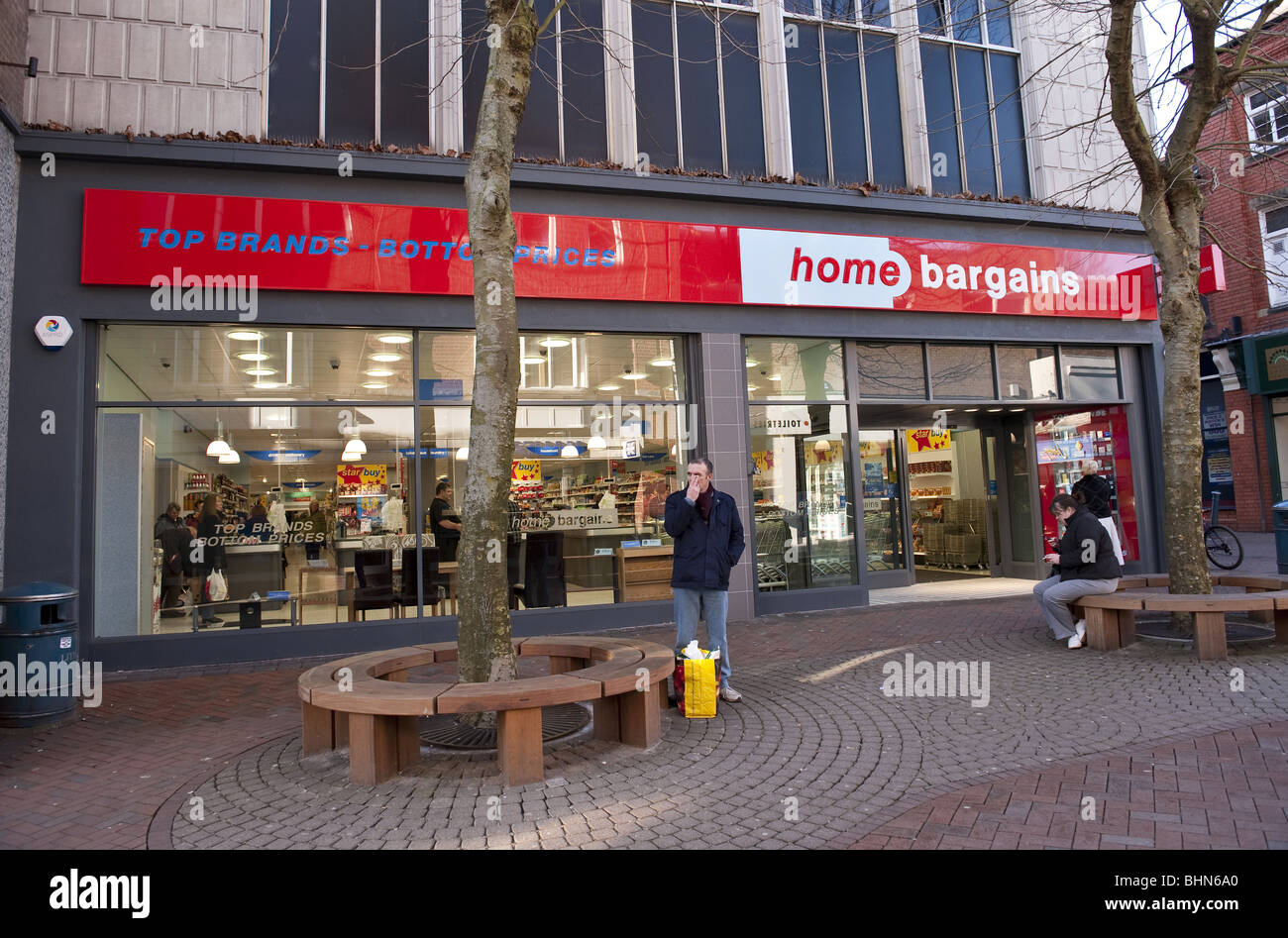 Externen Shop Fassade Home Schnäppchen Shop wo Top-Marken - Preisuntergrenzen auf schattigen Baum Menschen beim Einkaufen Hautpstraße gesäumt Stockfoto
