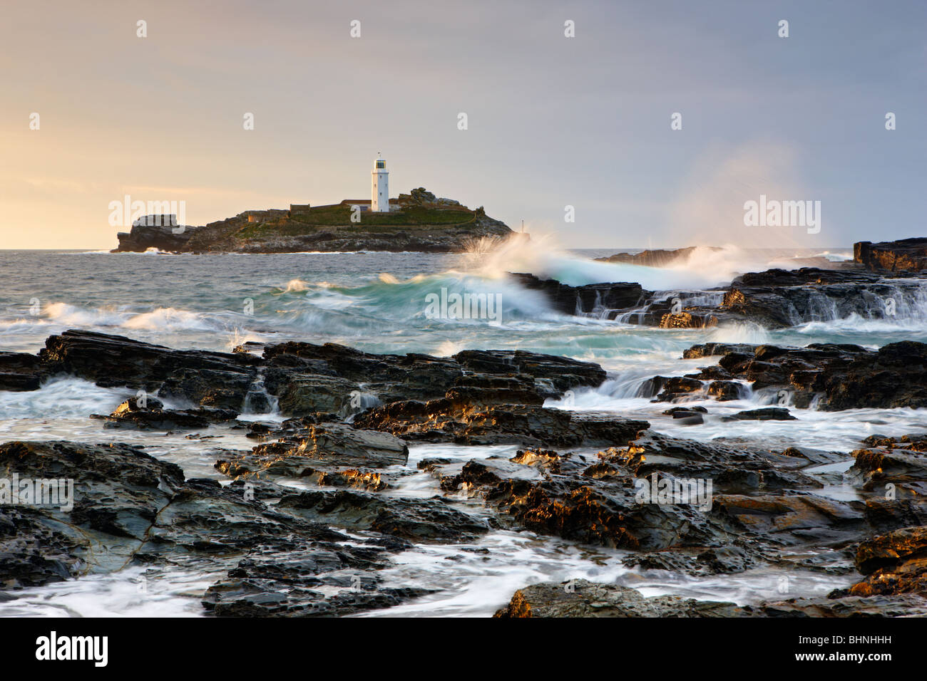 Atlantischen Wellen, die über die Felsen bei Godrevy Leuchtturm, St. Ives Bay Stockfoto