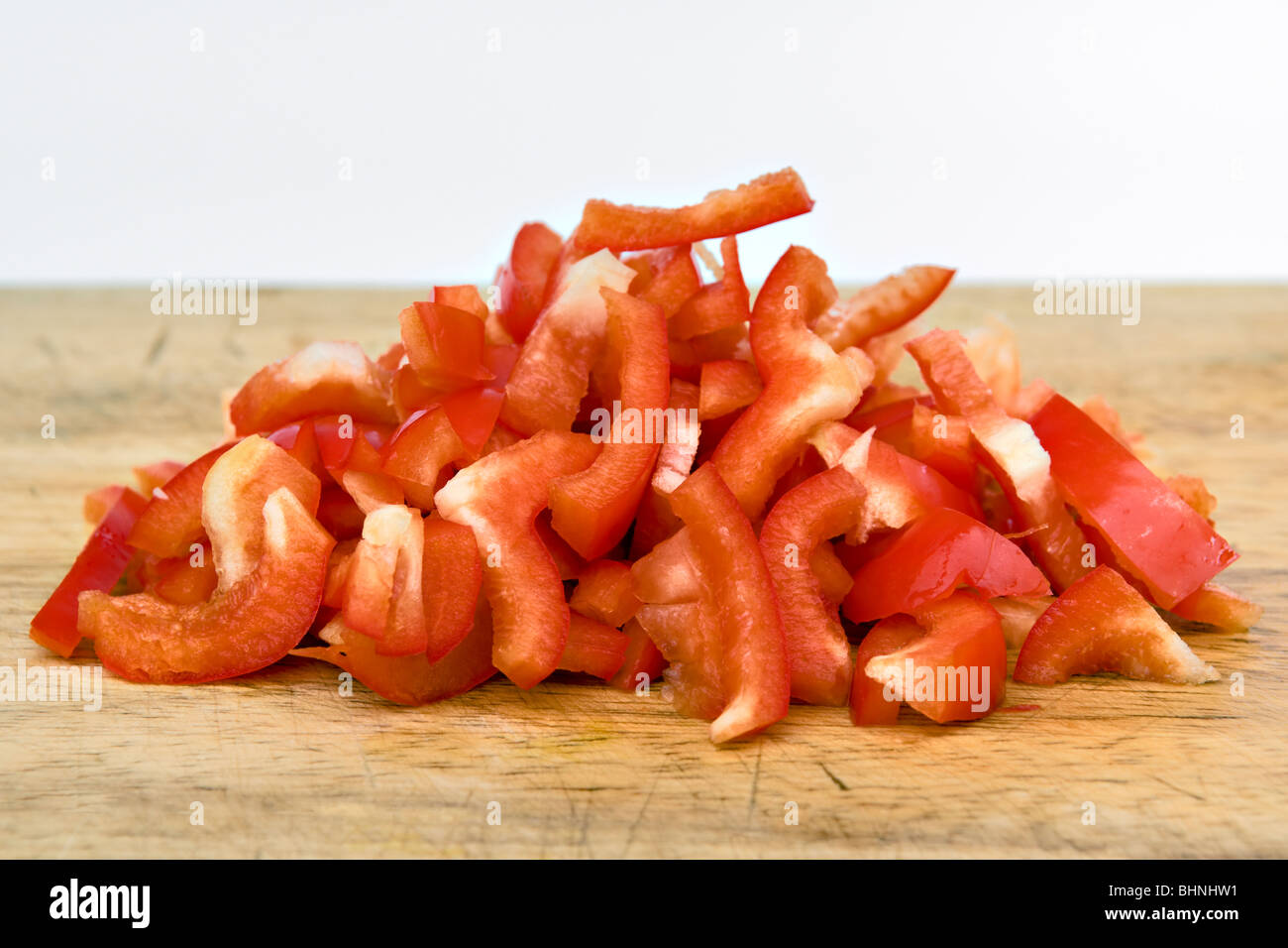Nahaufnahme von gehackten Paprika auf Schneidbrett aus Holz auf einem weißen Hintergrund Stockfoto