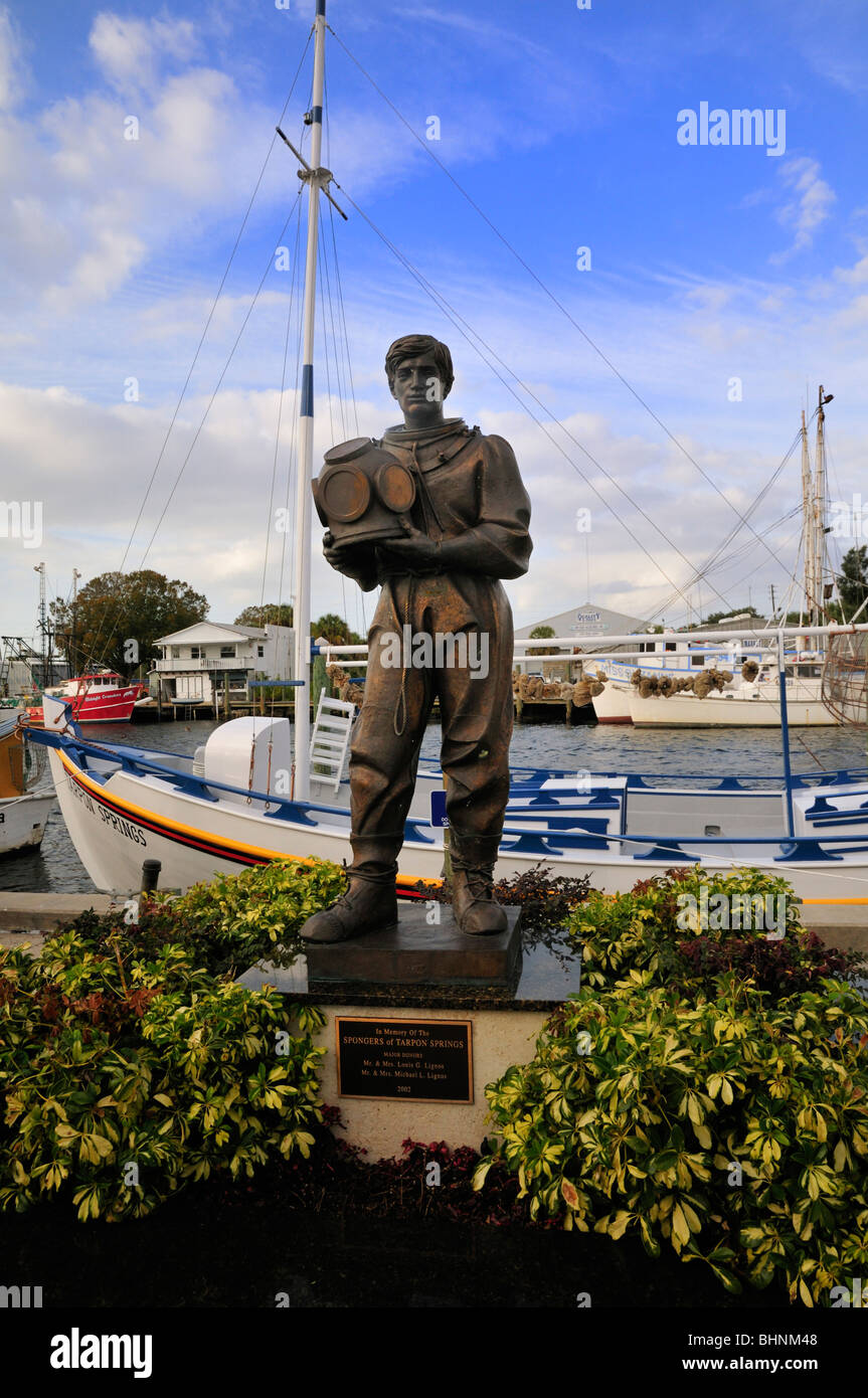 Statue eines jungen Schwamm Fischers steht vor einer Flotte von Schwamm Angelboote/Fischerboote am Hafen Tarpon Springs Stockfoto