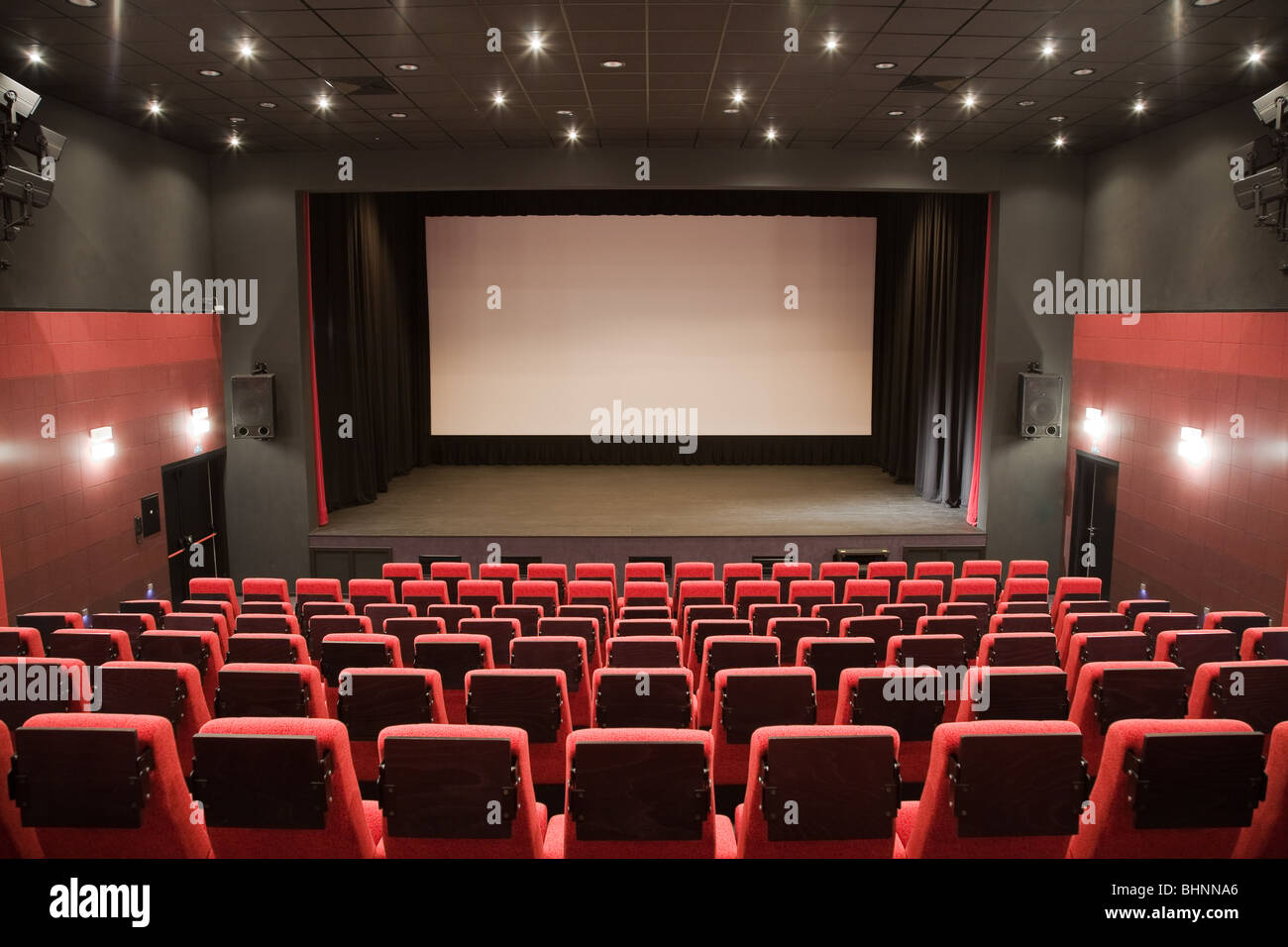 Leeren Kinosaal mit rote Stühle, Bühne und Projektion Schirm. Bereit für Ihr eigenes Bild hinzufügen. Stockfoto