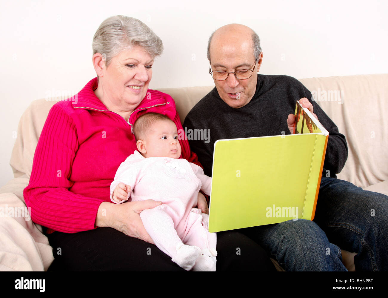 Familie sitzen zusammen auf der Couch, Baby Buch zu lesen. Großvater und Großmutter lesen grüne buchen Kleinkind Enkelin. Stockfoto