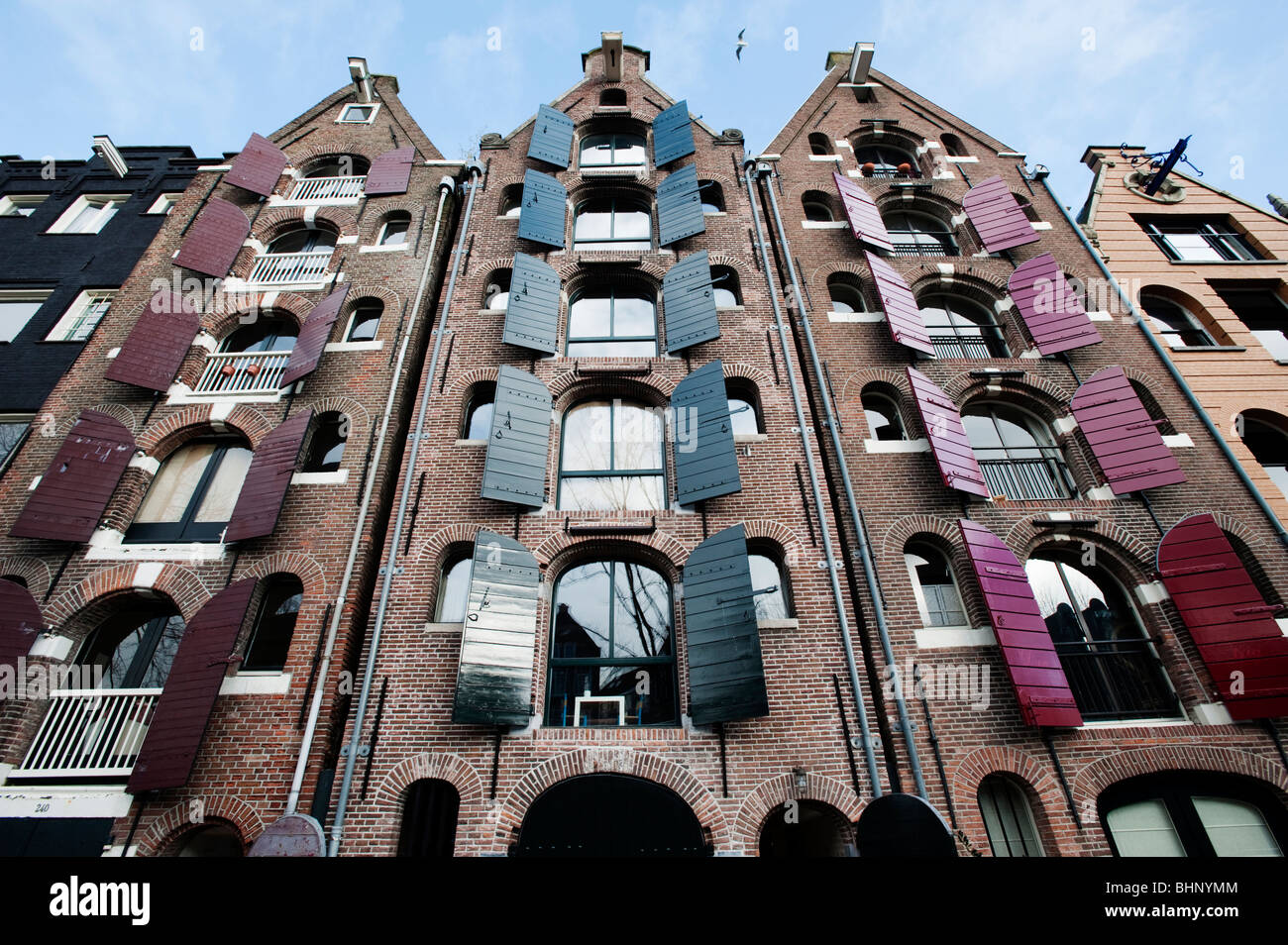 Häuser in Amsterdam; Traditionelle niederländische Häuser mit Fensterläden neben Kanal in Amsterdam, Niederlande Stockfoto