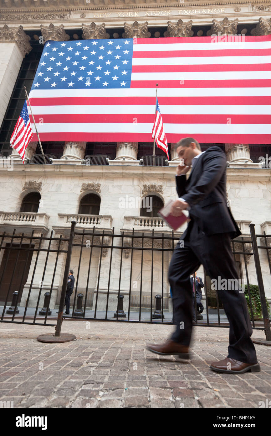New York Stock Exchange mit Business-Mann, vorbei an mit Handy in Bewegung verwischen mit US-Flagge im Hintergrund Stockfoto