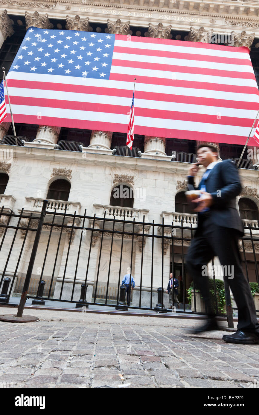 New York Stock Exchange mit Business-Mann, vorbei an mit Handy in Bewegung verwischen mit US-Flagge im Hintergrund Stockfoto