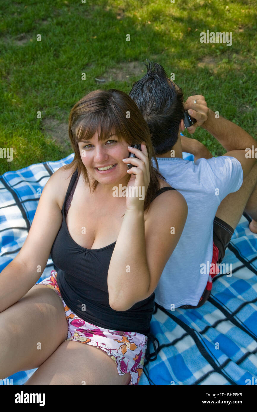 Junges Paar im Garten zu sitzen, sprechen jeweils am Handy Stockfoto