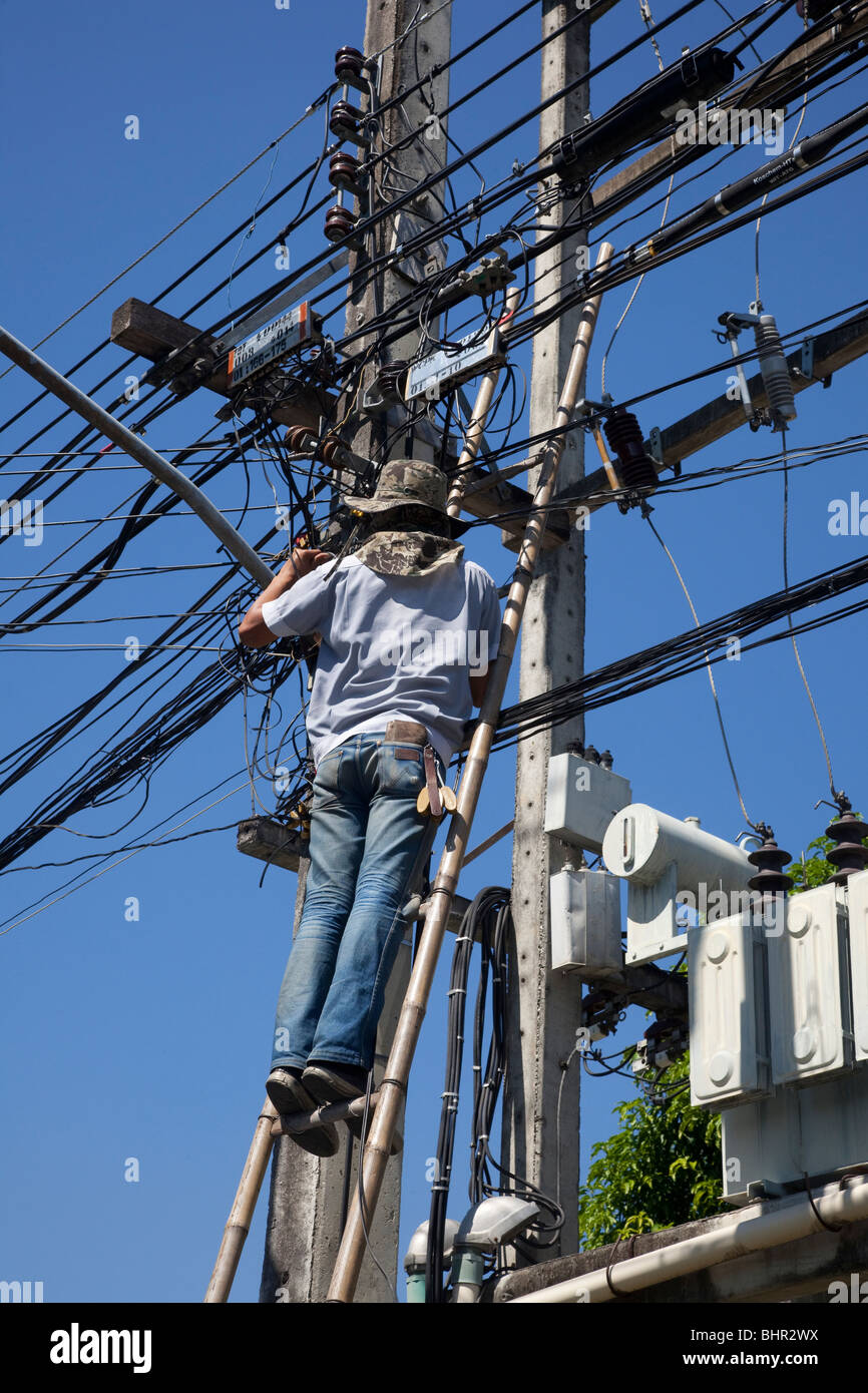 Elektriker Reparatur der Stromversorgung über Oberleitungen; Hausverkabelung in Chiang Mai Thailand, ohne Schutzausrüstung oder Ausrüstung. Stockfoto