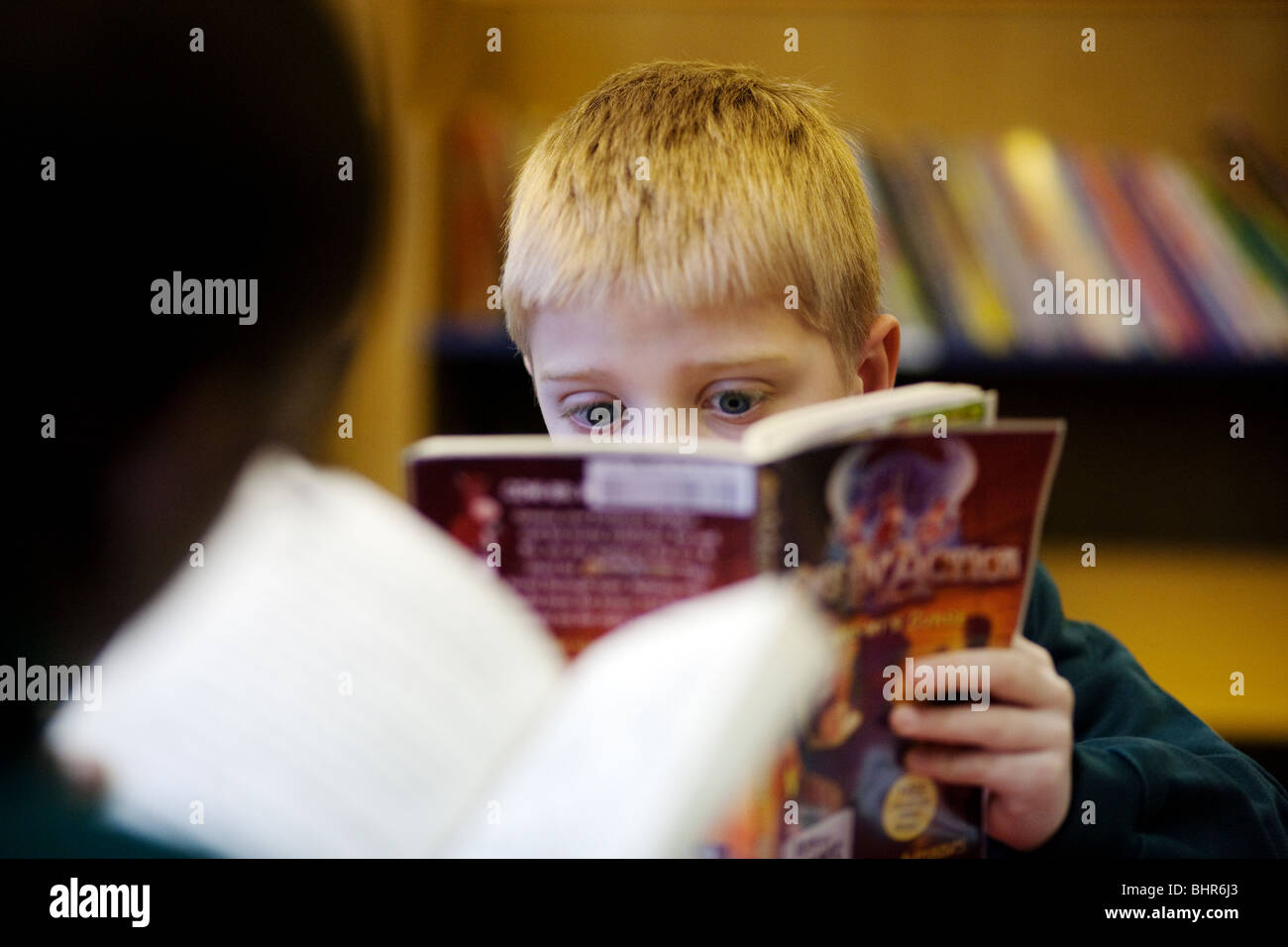 Ein Kind, das Lesen in der Bibliothek an einer Grundschule in Großbritannien Stockfoto