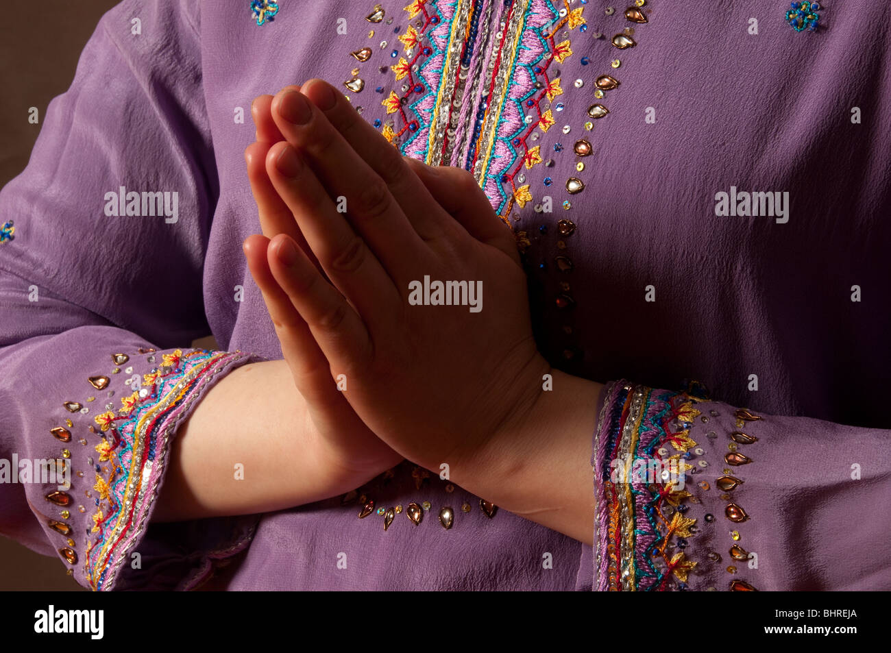 Nahaufnahme eines weiblichen Hände im Gebet Position vor bunten lila indischen Stil bestickt kameeze Stockfoto