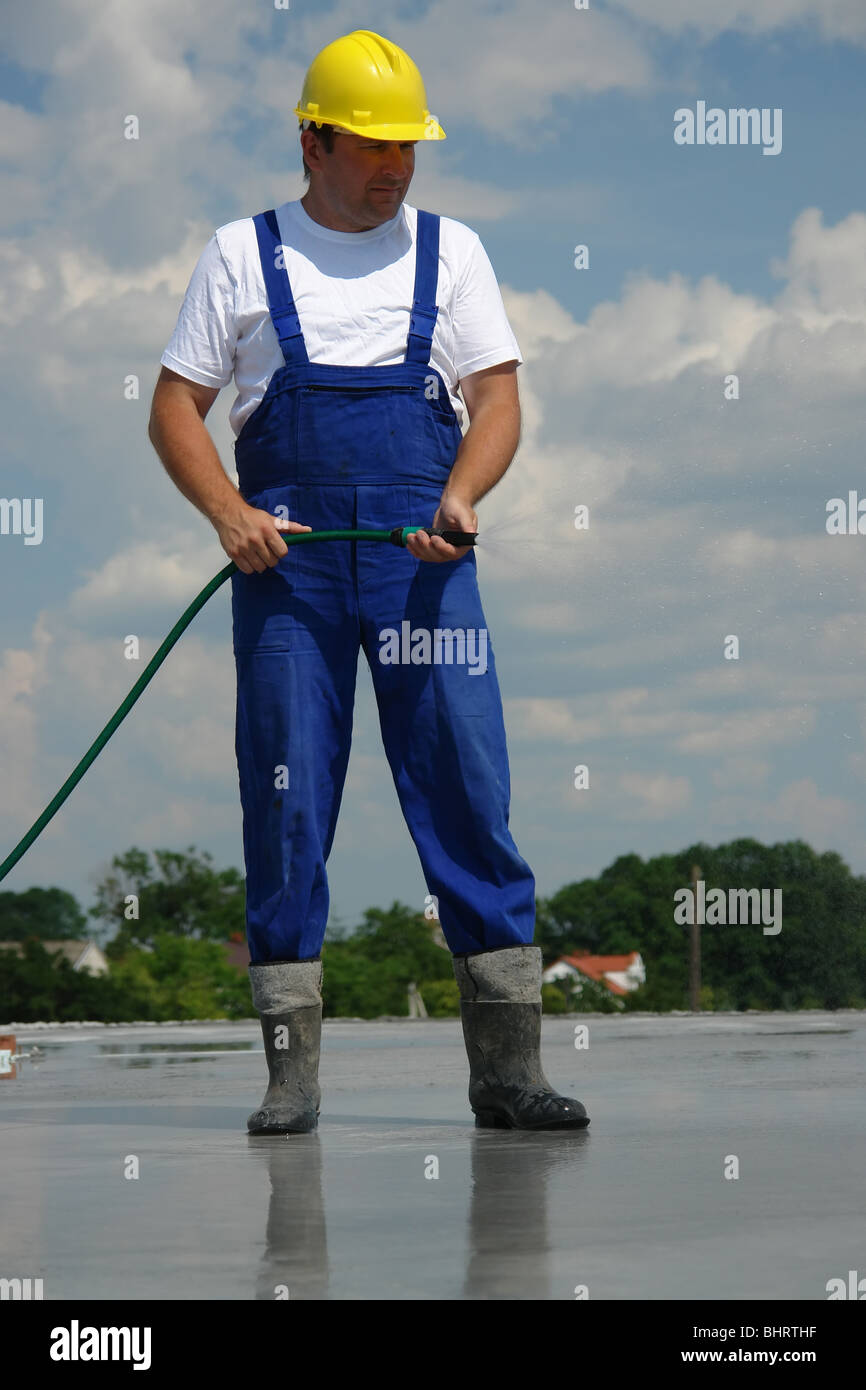 Bauarbeiter, frischen Betonplatte mit einem Schlauch Bewässerung Stockfoto