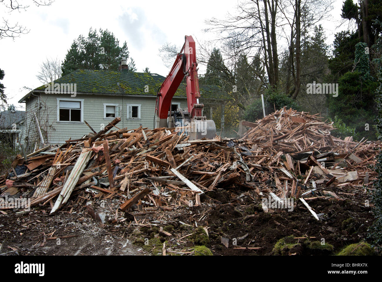 Link-Belt Bagger reißt dann altes Haus in staubigen zersplitterte Rahmung Holz Beton Schutt zermalmt Stockfoto