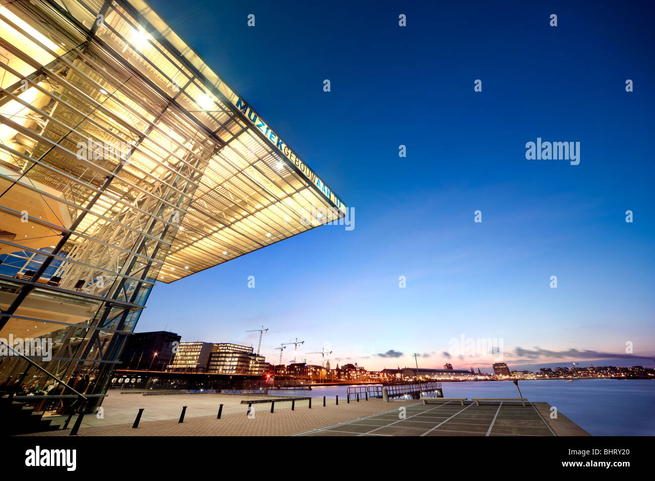 Amsterdam-Musik-Gebäude auf dem IJ und die Star Ferry Restaurant in der Abenddämmerung mit Blick auf den Hauptbahnhof und den Hafen. Stockfoto