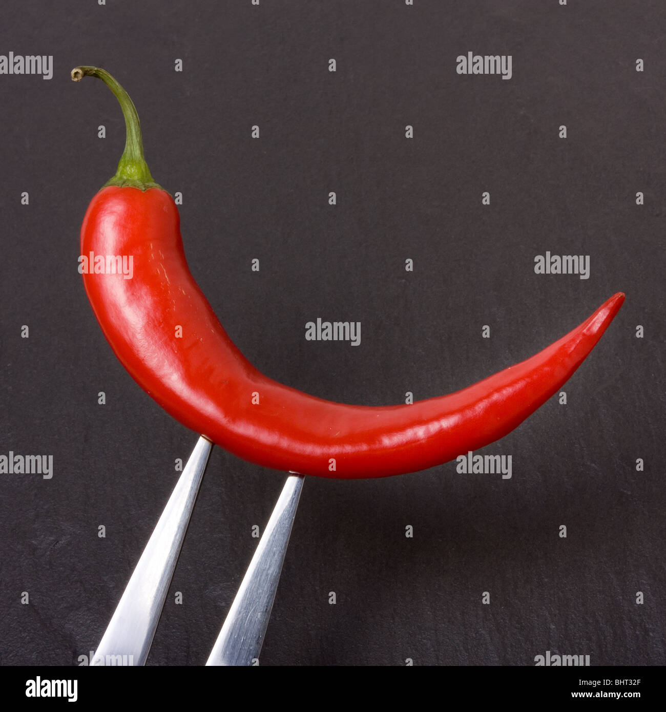 Lebhafte rote Chili mit Gabel dunklen Schiefer Hintergrund aufgespießt. Stockfoto