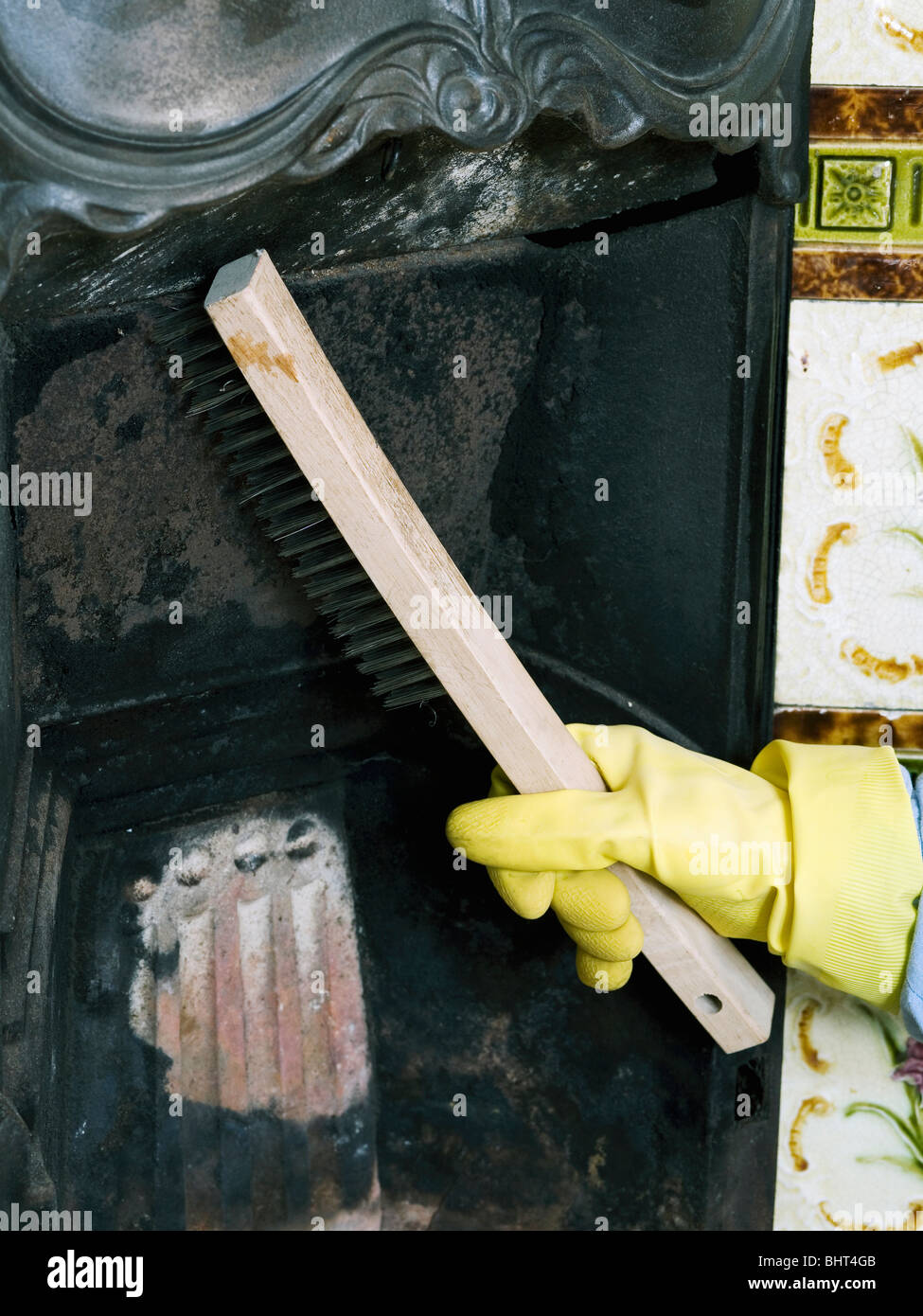 Nahaufnahme der Hand tragen Kautschuk Handschuh Reinigung und Renovierung von alten gusseisernen Kamin Stockfoto