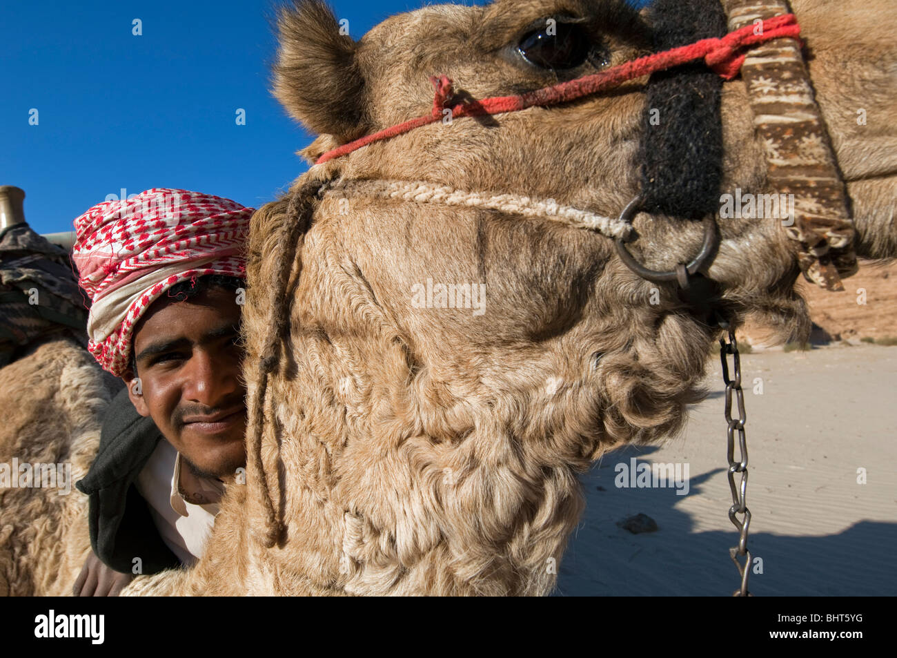 Nomadische Beduinen junge stellt für Kamera mit seinem Kamel an seiner Seite Stockfoto