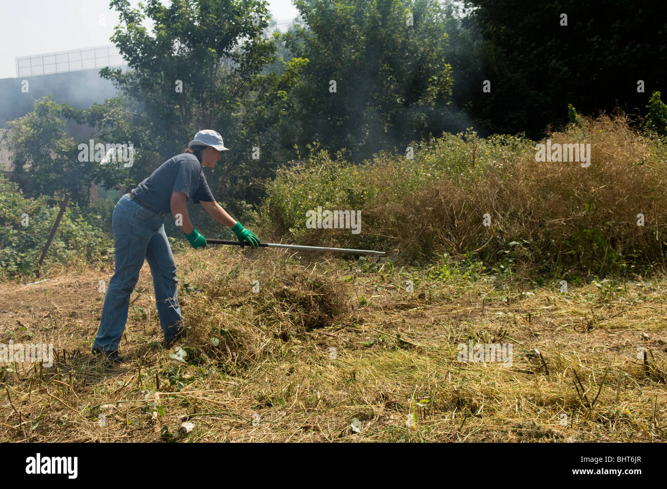 Frau clearing überwucherten Zuteilung Plot und brennen das Schneiden Unkraut Stockfoto