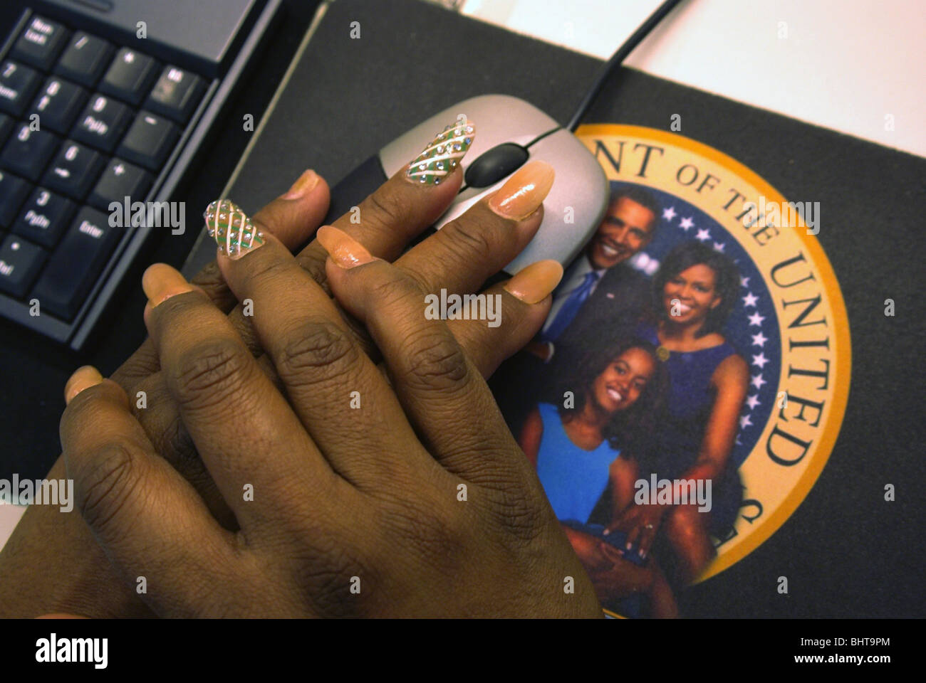 Afrikanische amerikanische Frau, die ihre Nägel Anzeigen auf einem Mousepad mit dem Bild der Familie Obama eingerichtet Stockfoto