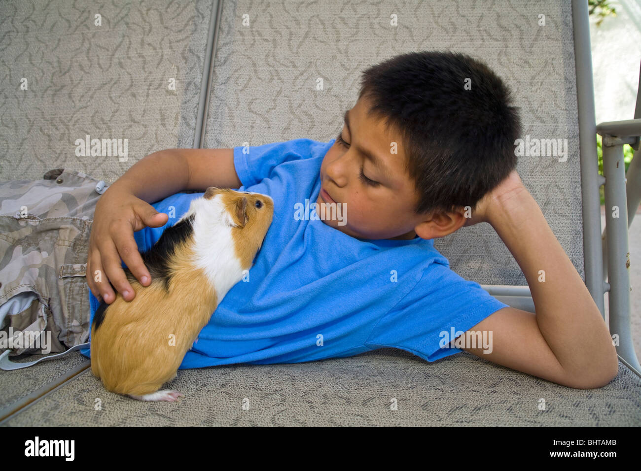 8-9 Jahre Alter spanischer Junge entspannen entspannt entspannt relaxen mit seinem Meerschweinchen auf außen Schaukel spielen. Vereinigten Staaten Herr © Myrleen Pearson Stockfoto
