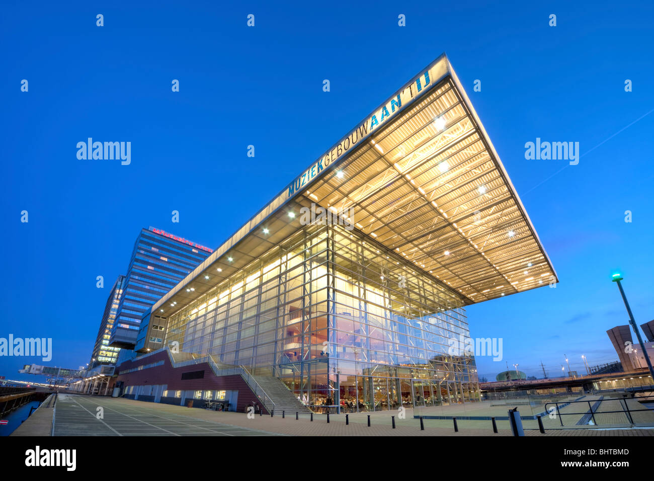 Amsterdamer Muziekgebouw Aan ' t IJ, Musik-Gebäude an der IJ; Star Ferry-Restaurant in der Abenddämmerung. Mövenpick Hotel; Kreuzfahrt-Terminal. Stockfoto