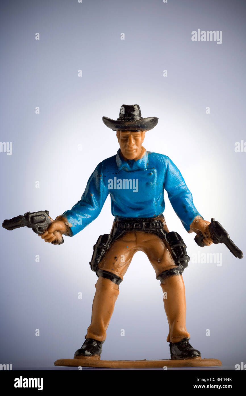 Miniatur-Spielzeug-Cowboy zeichnen beide Pistolen Stockfoto