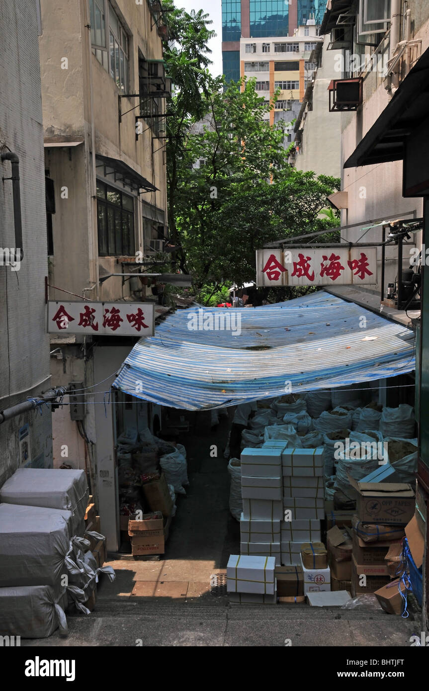Weiße Kisten und Säcke Trockenfutter gestapelt unter einem Kunststoff Baldachin in einer schmalen Leiter Gasse, in der Nähe von Queens Road West, Hong Kong Stockfotografie
