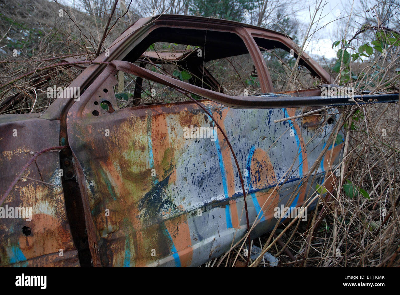 Gestohlen, ausgebrannt, verrostet, verlassen Auto mit den Überresten des Graffiti. Stockfoto