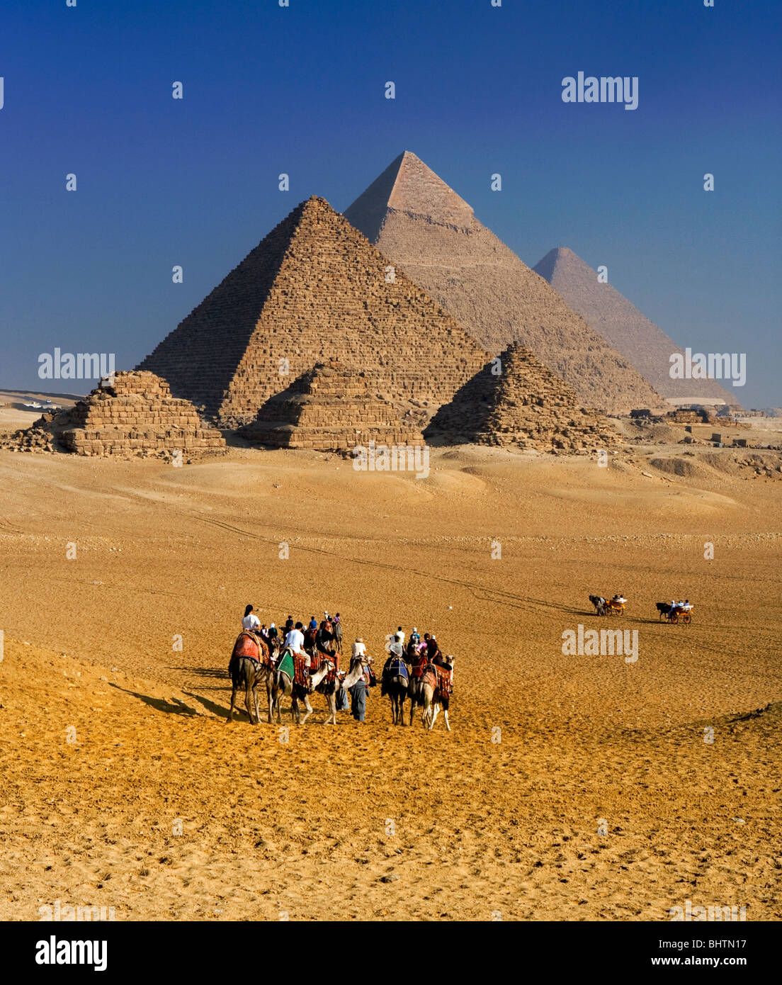 Touristen, Kamelreiten bei den Pyramiden von Gizeh, Kairo, Ägypten. Stockfoto