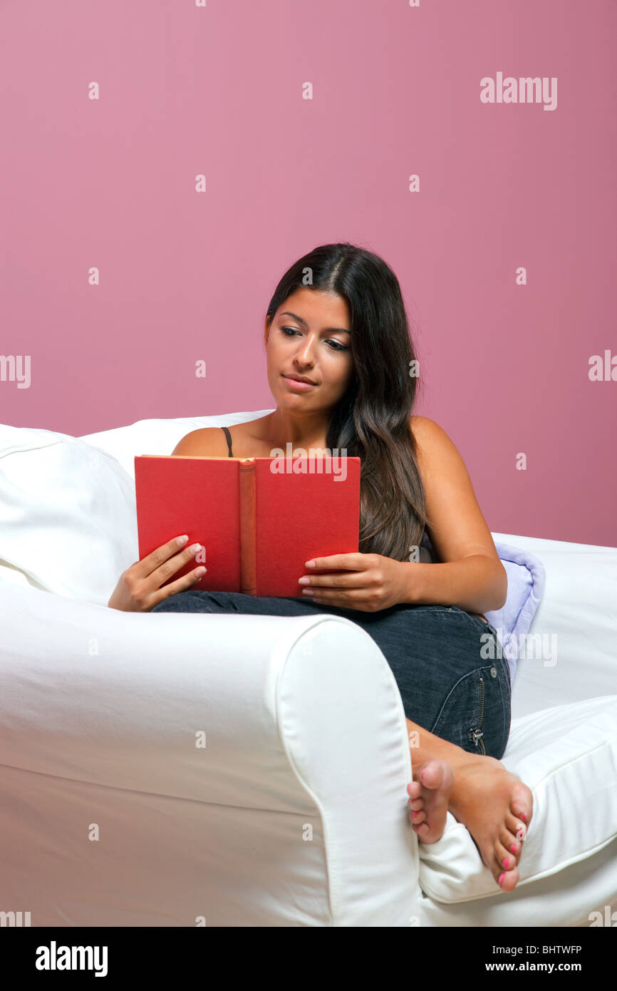 Frau in Freizeitkleidung saß in einem Sessel, ein Buch zu lesen Stockfoto