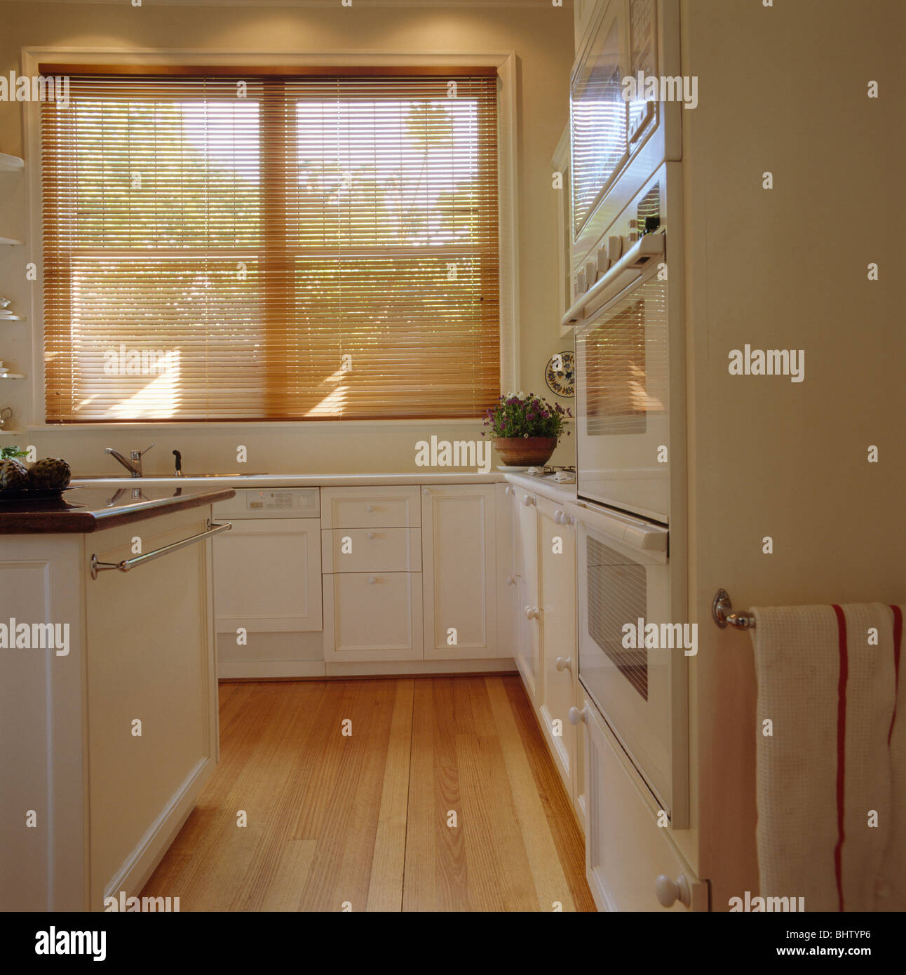 Lattenrost aus Holz Jalousie am Fenster in modernen weißen Küche mit Holzboden Stockfoto