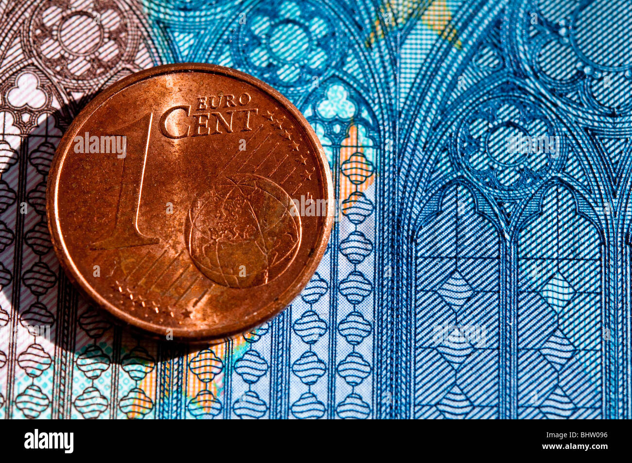 1-Cent-Euro-Münze mit Detail aus einem 20-Euro-Schein als Hintergrund Stockfoto