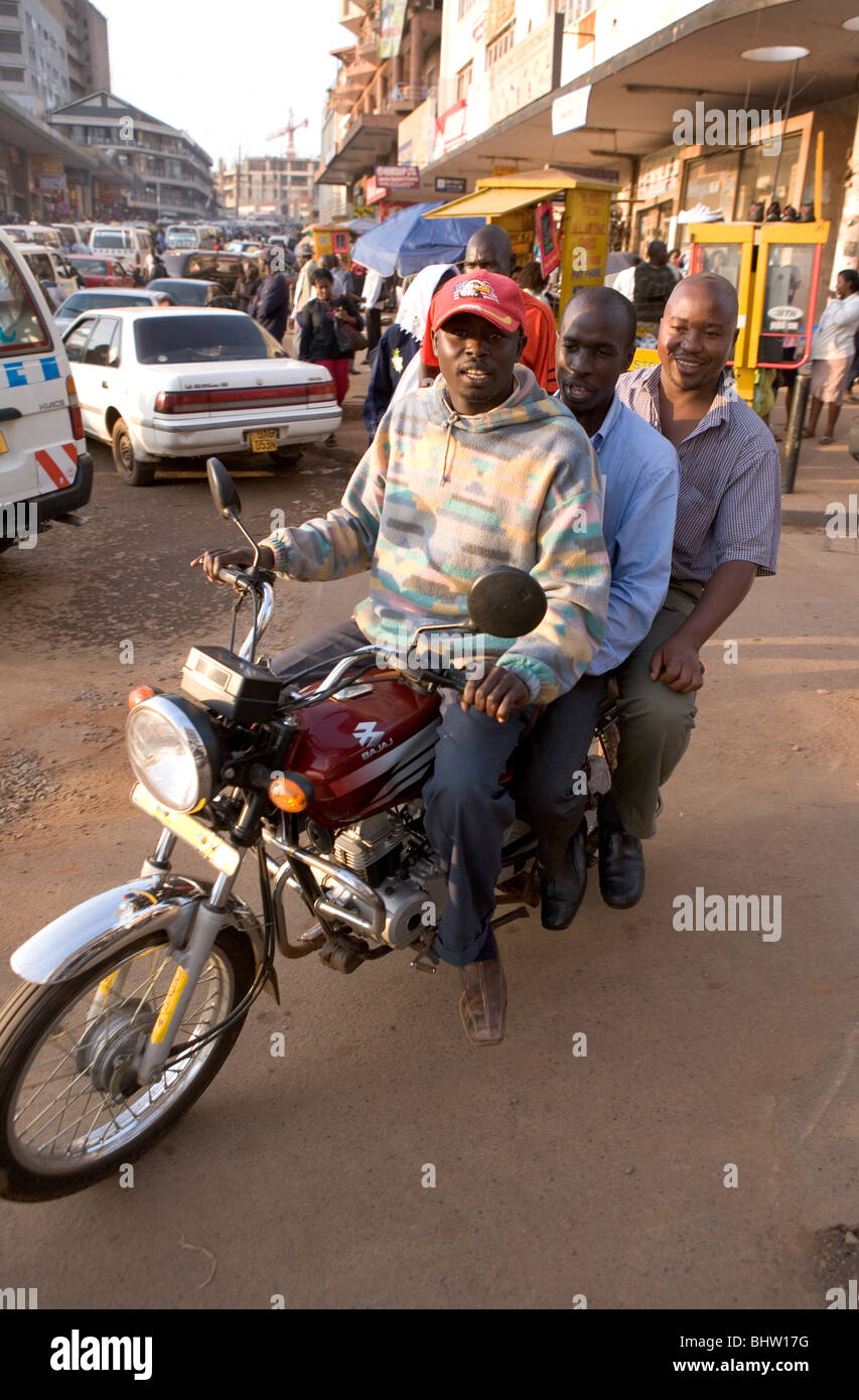 Drei Männer, die Reisen mit dem Motorrad in einer belebten Straße in Kampala, Uganda Stockfoto
