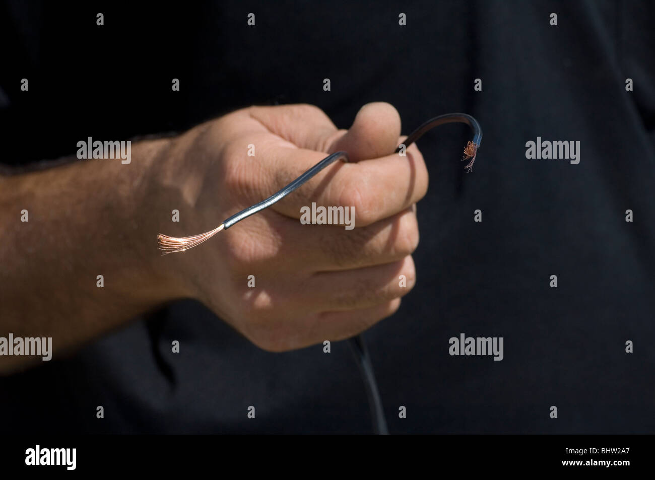 Technikers Hand hält einen schwarzen Draht Stockfoto