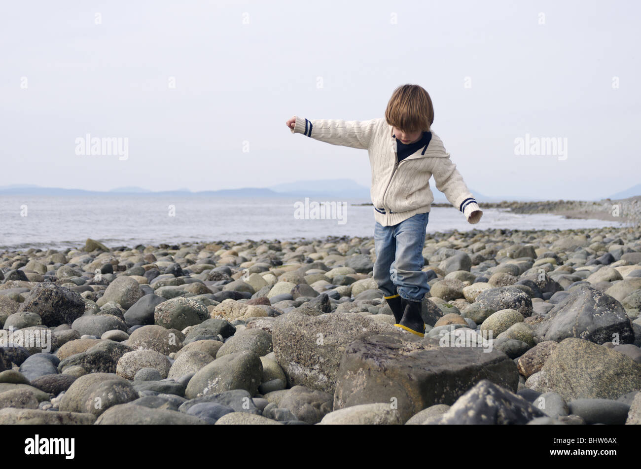 Junge navigiert einen felsigen Strand Stockfoto