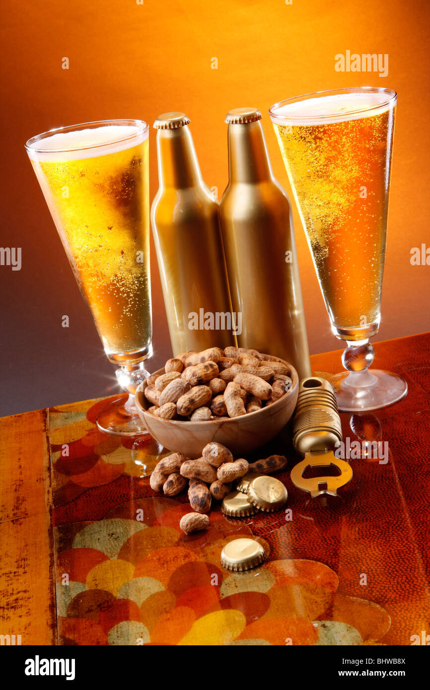 Goldene Bier, geröstete Erdnüsse, Öffner und Kappen Stockfoto