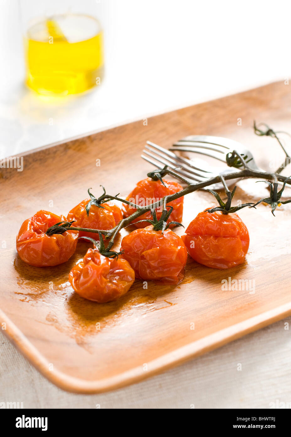 Gebratene Kirschtomaten auf eine Portion Plater mit Olivenöl im Hintergrund Stockfoto