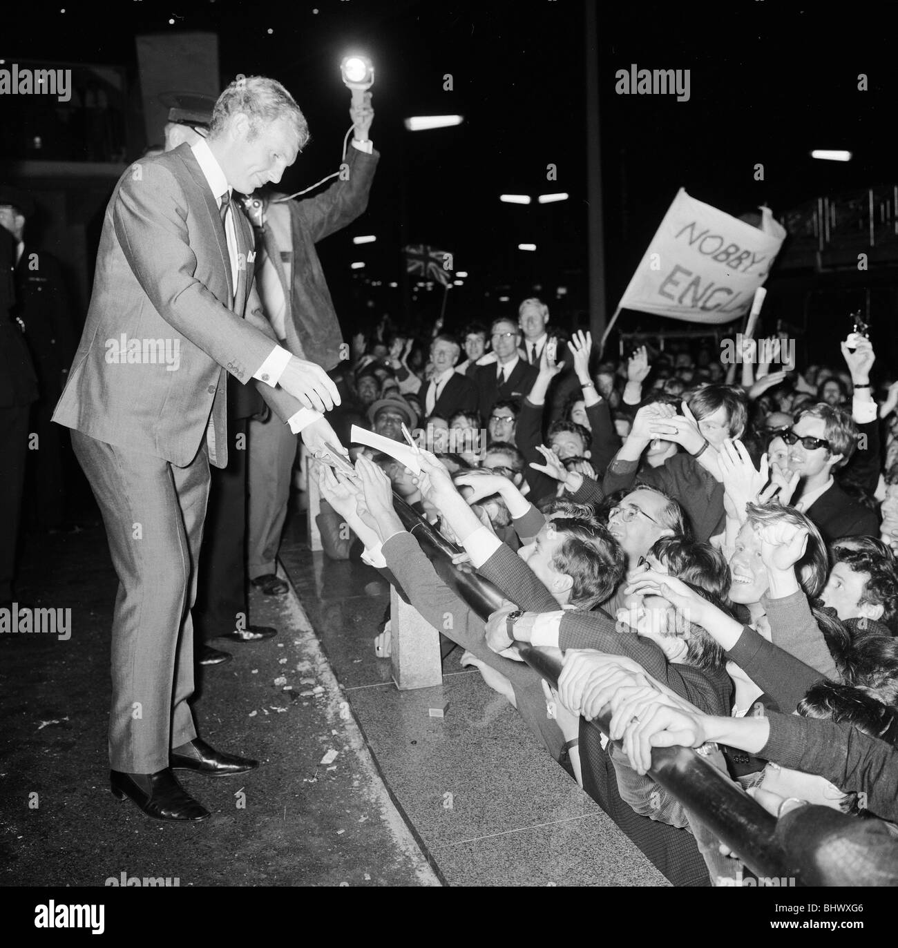 1966-World-Cup-Turnier in England. Ein Welt-Cup-Bankett fand für das Siegerteam England im Royal Garden Hotel nach ihrem Sieg über Westdeutschland im Finale im Wembley-Stadion statt. England-Kapitän Bobby Moore schüttelt Hände mit jubelnden Fans außerhalb, 31. Juli 1966. Stockfoto