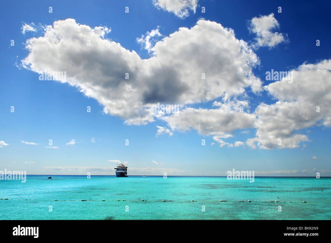Kreuzfahrtschiff vor Anker im Wasser der bunten Karibik mit Wolken Stockfoto