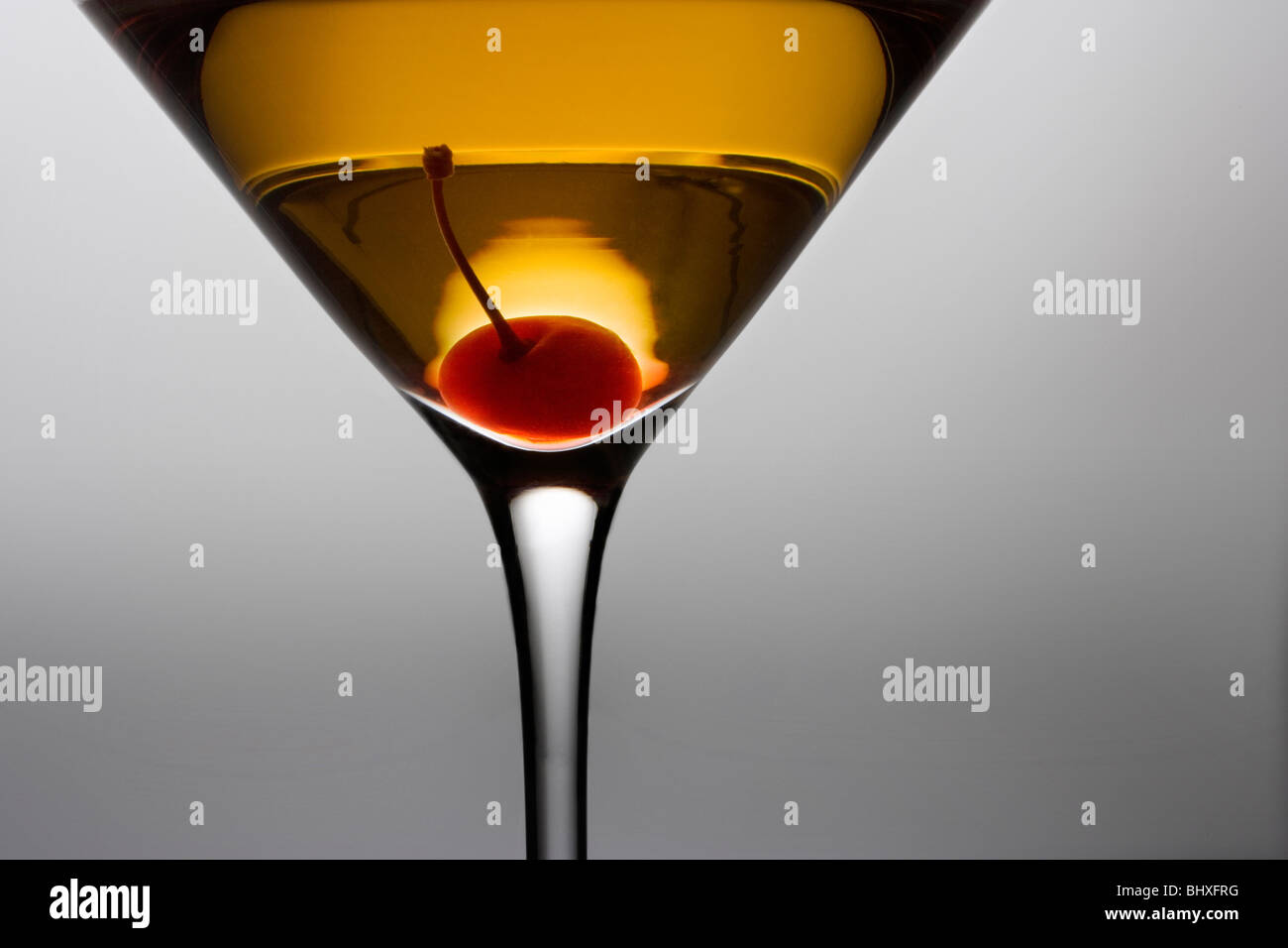 Manhattan oder Rob Roy cocktail mit Kirsche garnieren hautnah auf grauem Hintergrund Stockfoto