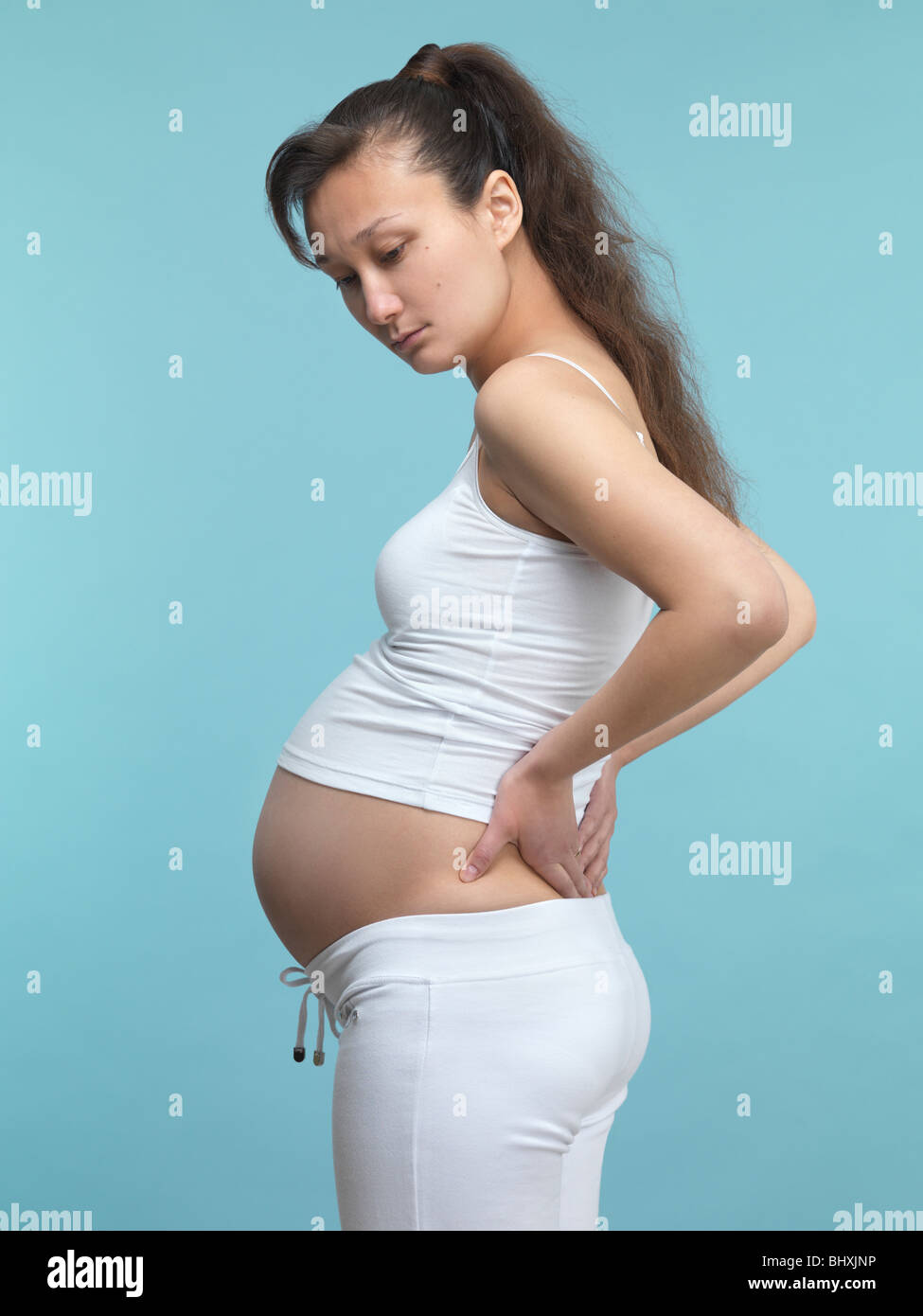 Junge schwangere Frau reibt ihren Rücken Stockfoto