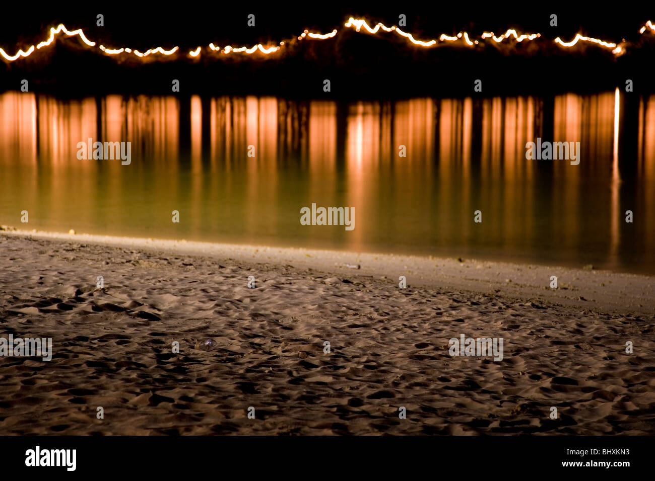 Lichtreflektierende aus dem Wasser an einem Strand in der Nacht. Stockfoto