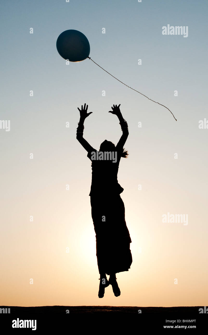 Silhouette eines indischen Mädchens fangen einen Ballon bei Sonnenuntergang Stockfoto