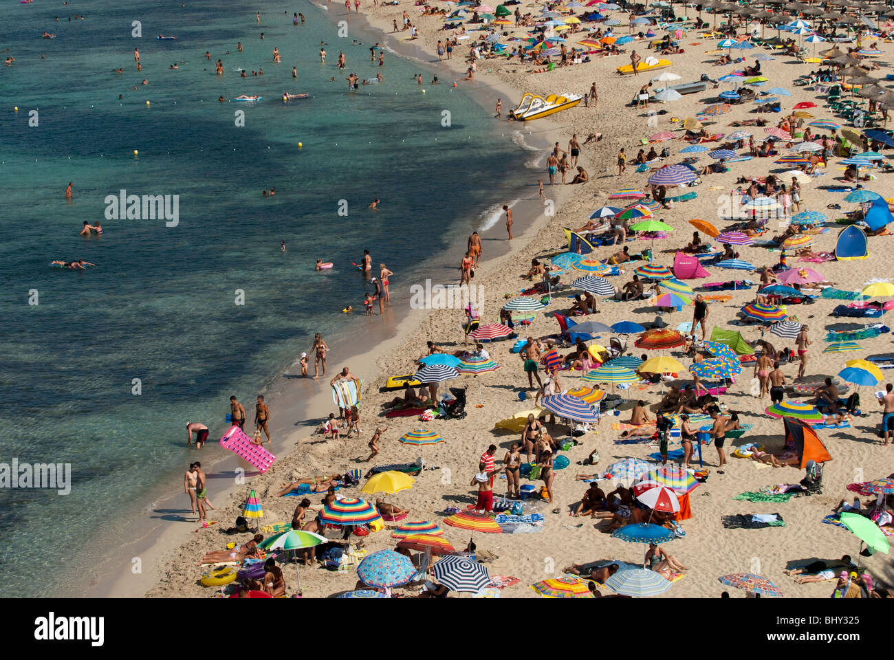 Überfüllten Strand an einem heißen Sommertag mit vielen farbigen Sonnenschirmen Stockfoto