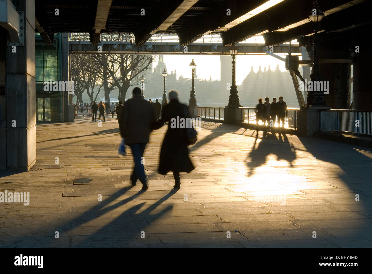 Ein paar wenige unter Hungerford Bridge und der Golden Jubilee Bridges im Zentrum von London in goldenes Licht getaucht Stockfoto