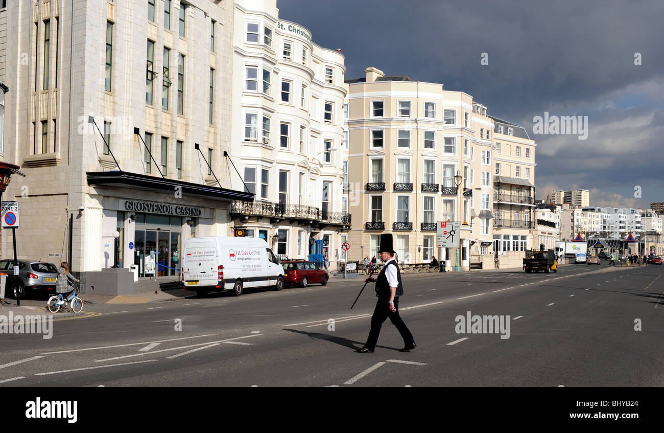 Mann mit riesigen hohen Hut beim Überqueren der Straße entlang Brighton Seafront UK Stockfoto