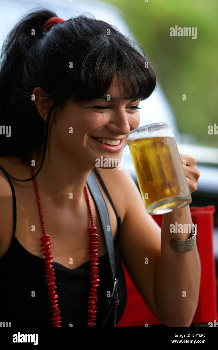 Mitte der zwanziger Jahre hispanic Frau lachen, trinken ein volles Glas Bier in einem Straßencafé Stockfoto