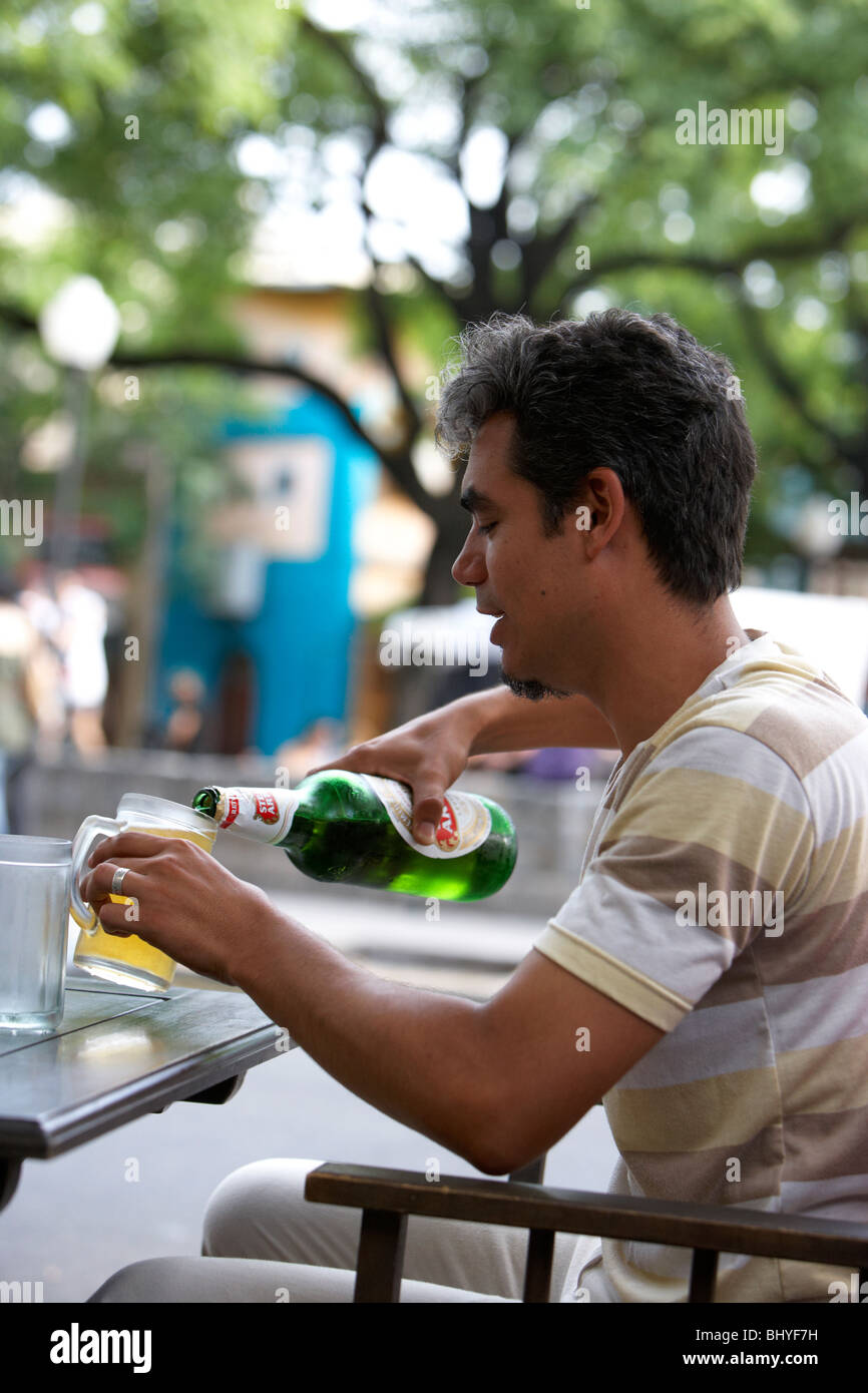 Anfang der dreißiger Jahre hispanic Mann gießen ein Glas Bier in einem Straßencafé Stockfoto